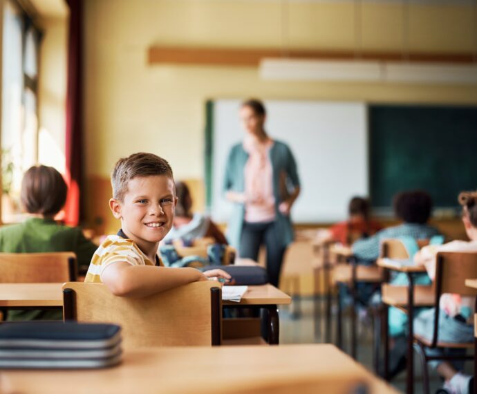 Happy elementary student in the classroom looking at camera.